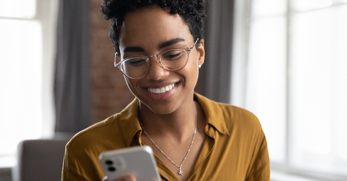 Happy Afro American young business woman in glasses using smartphone