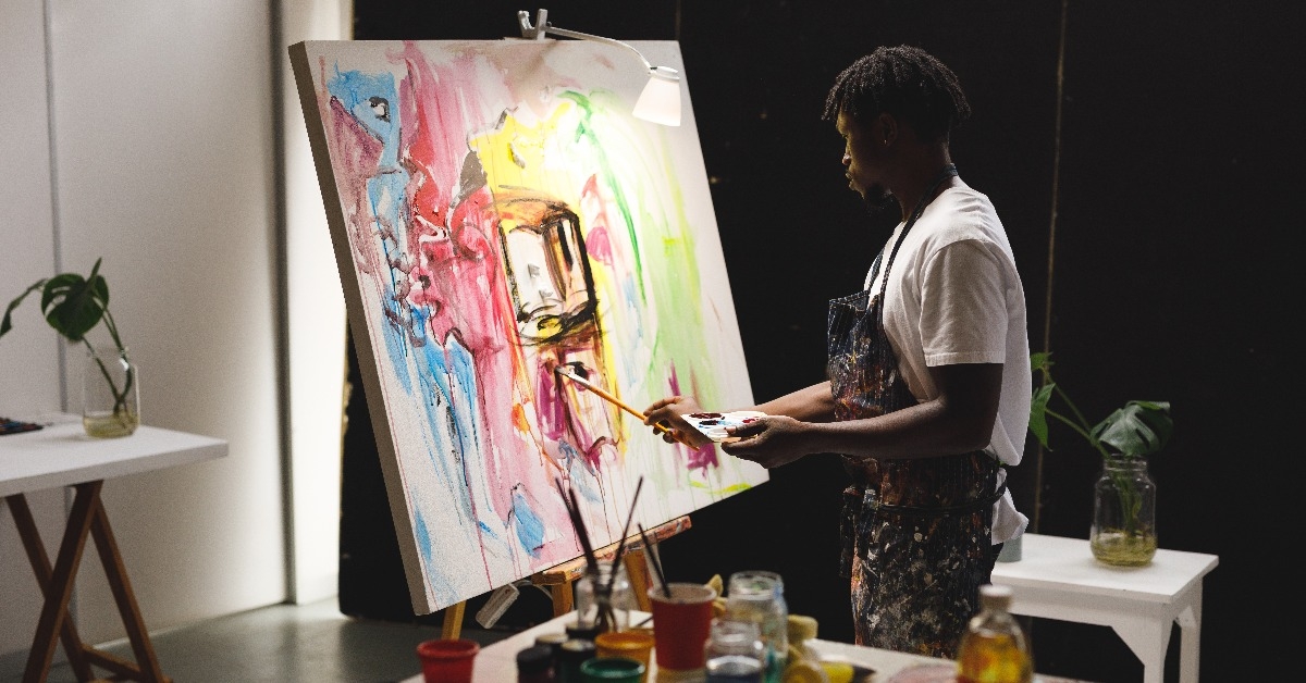 male painter at work painting on canvas in art studio