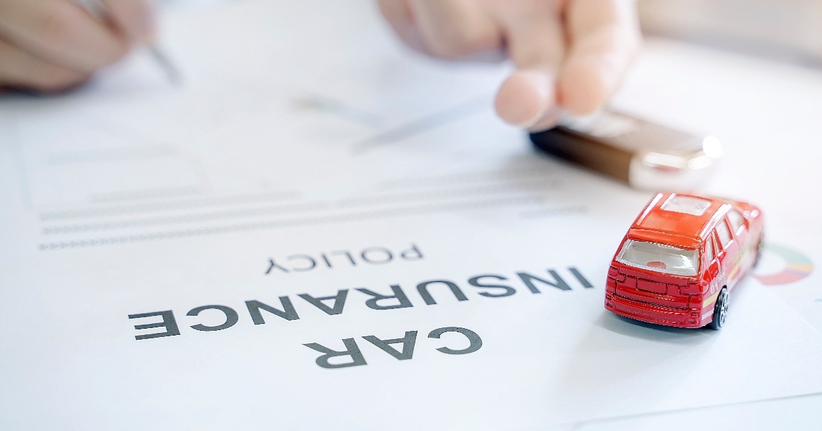 Car insurance policy with red car toy and blur image of man hand