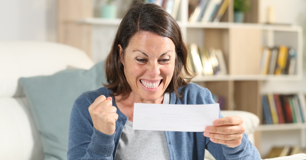 Excited adult woman checking receipts at home