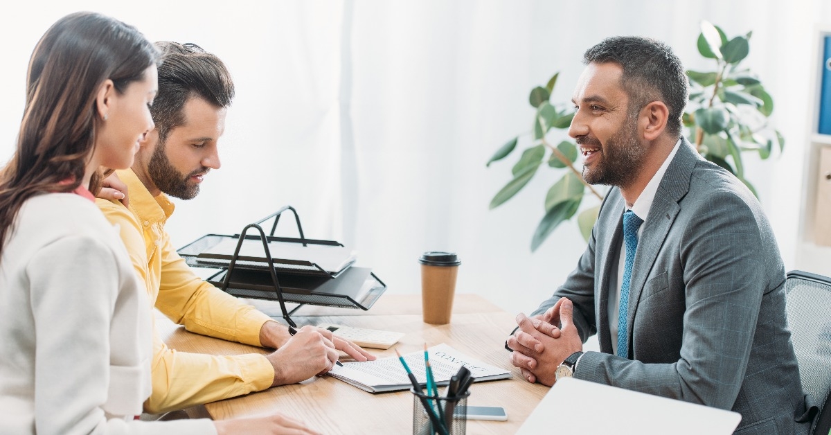 advisor and woman sitting at table wile investor signs a document