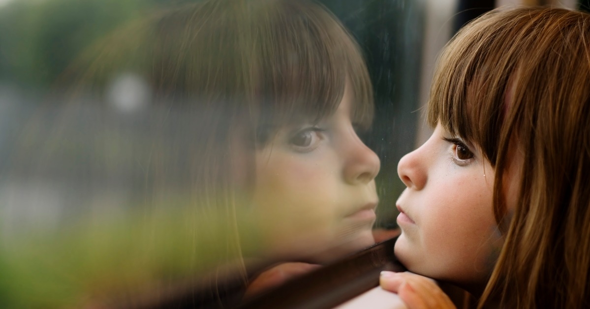 Little girl looking through window
