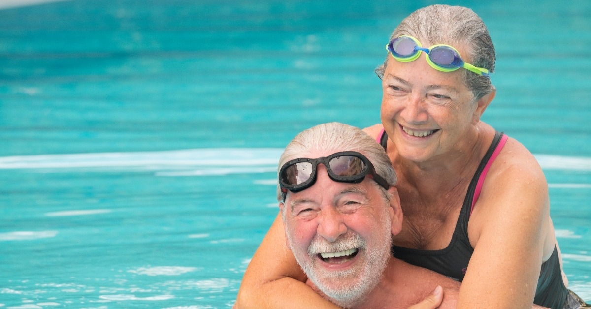 two seniors hugged in the water of swimming pool 