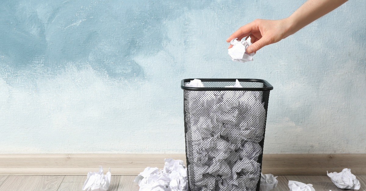 Woman throwing crumpled paper ball into basket
