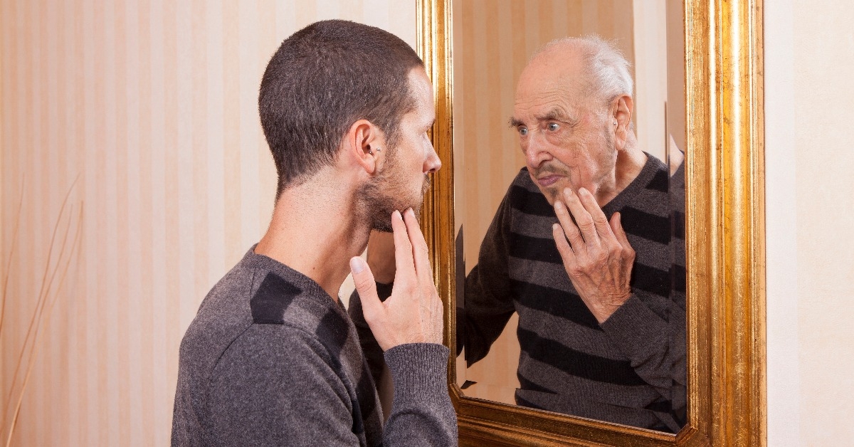 young man looking at an older himself in the mirror