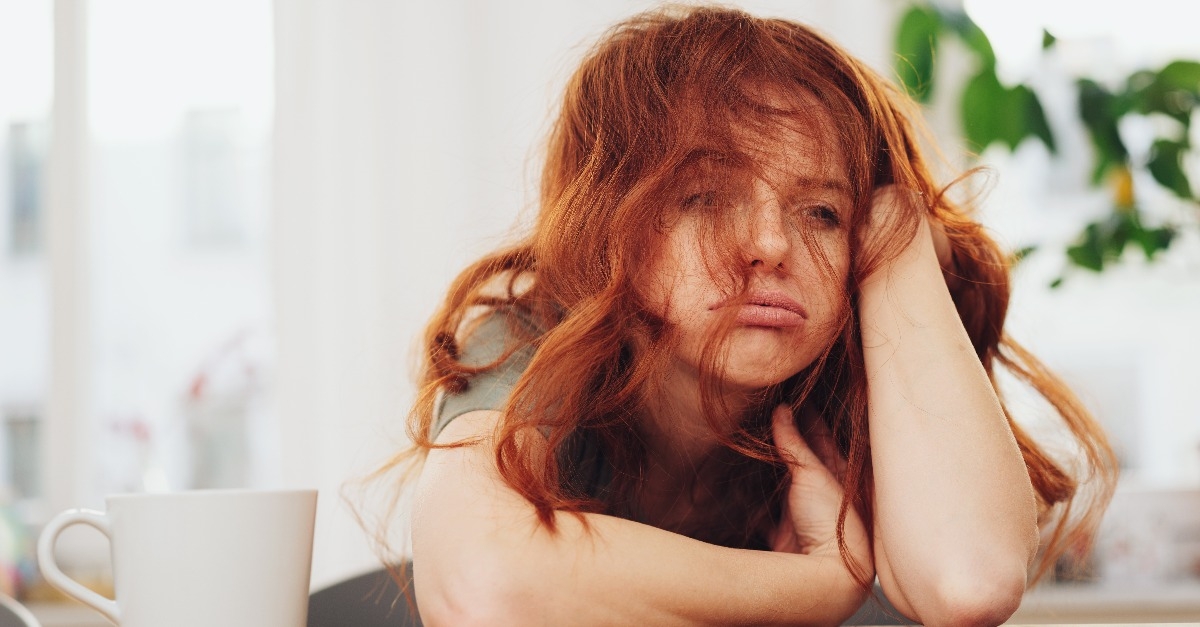 Red-haired girl sitting at table with boring face