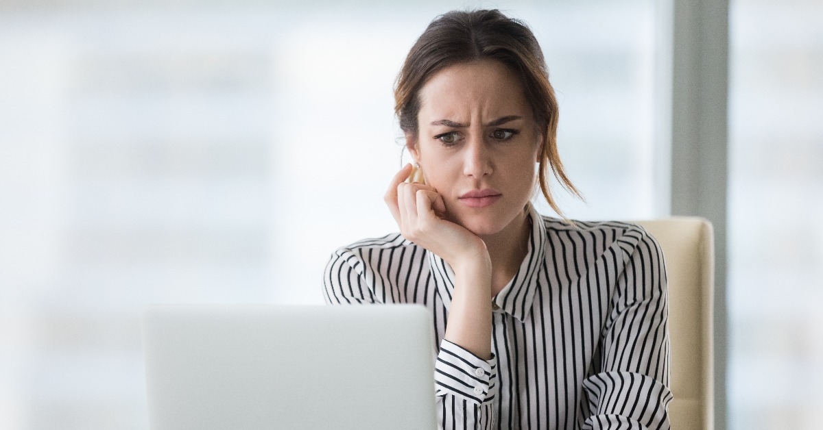 confused businesswoman annoyed by online problem looking at laptop