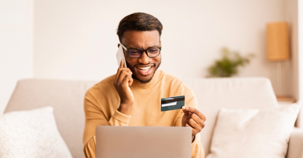 Man talking on phone using credit card laptop