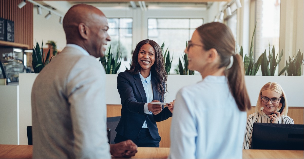 smiling concierge helping two guests check in to a hotel