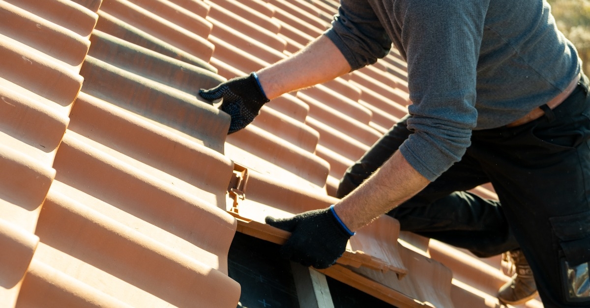worker hands installing yellow ceramic roofing tiles 