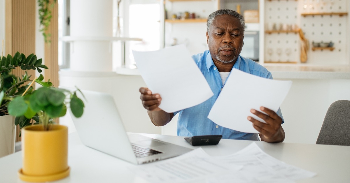 african pensioner sitting at home and looking at bills he has to pay