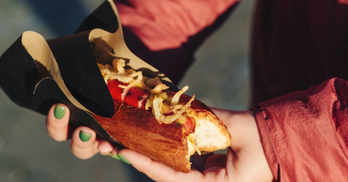 woman holding fresh hot dog with grilled sausage
