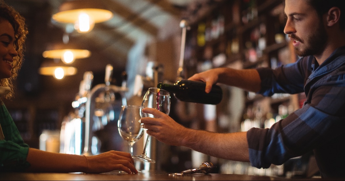 male bar tender pouring wine in glasses