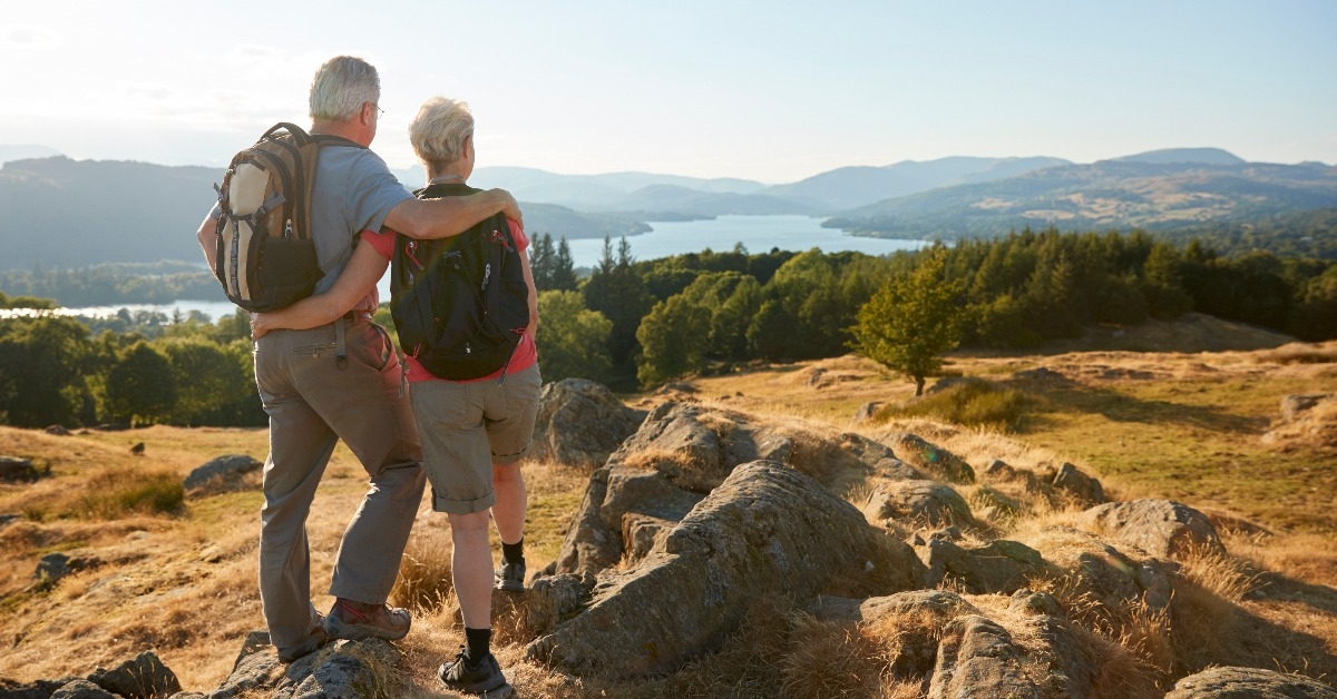 senior couple standing at top of hill on hike