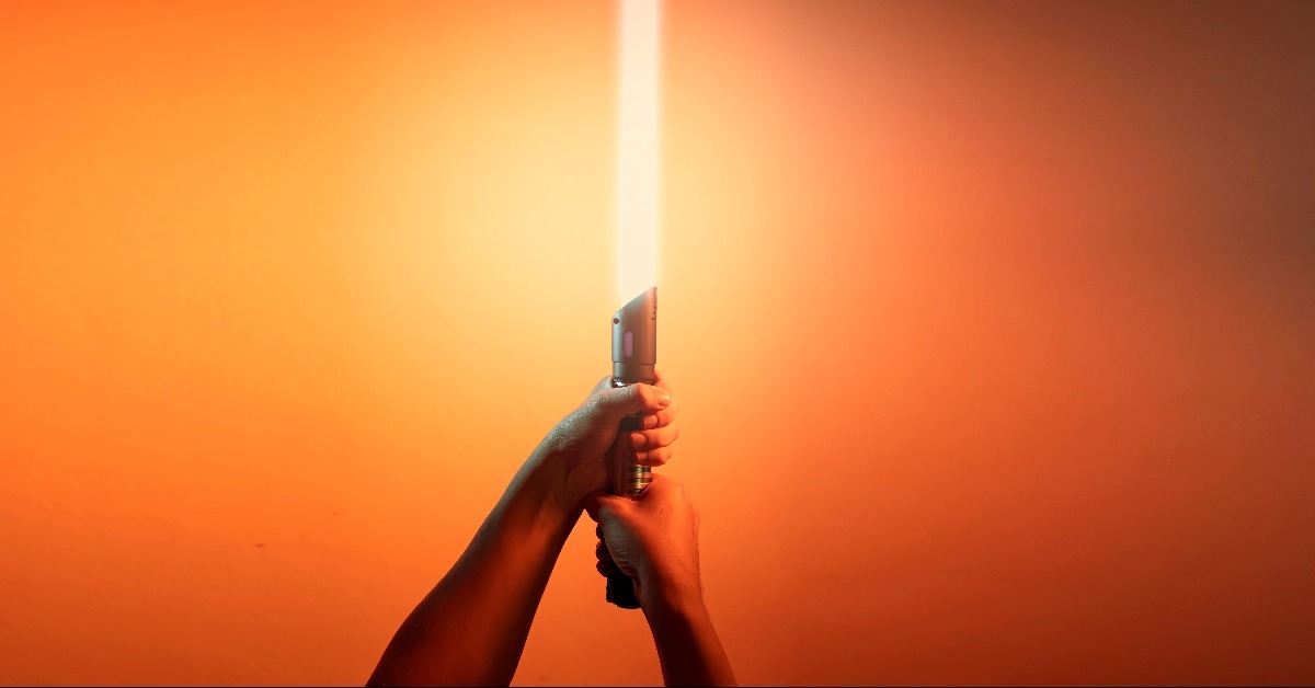 a fantastic laser sword lightsaber in the hands of a man