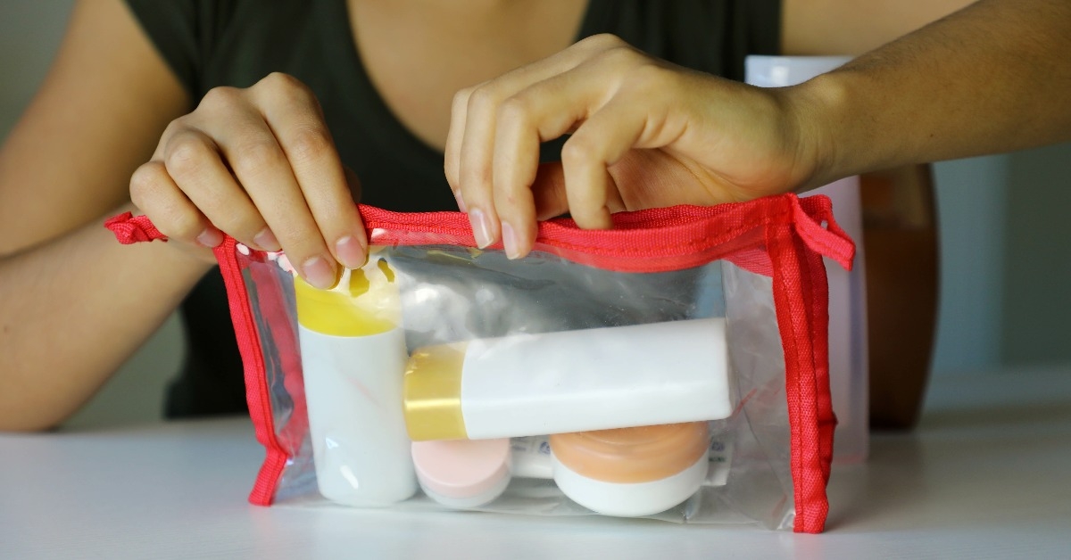 woman closing transparent bag with travel kit 