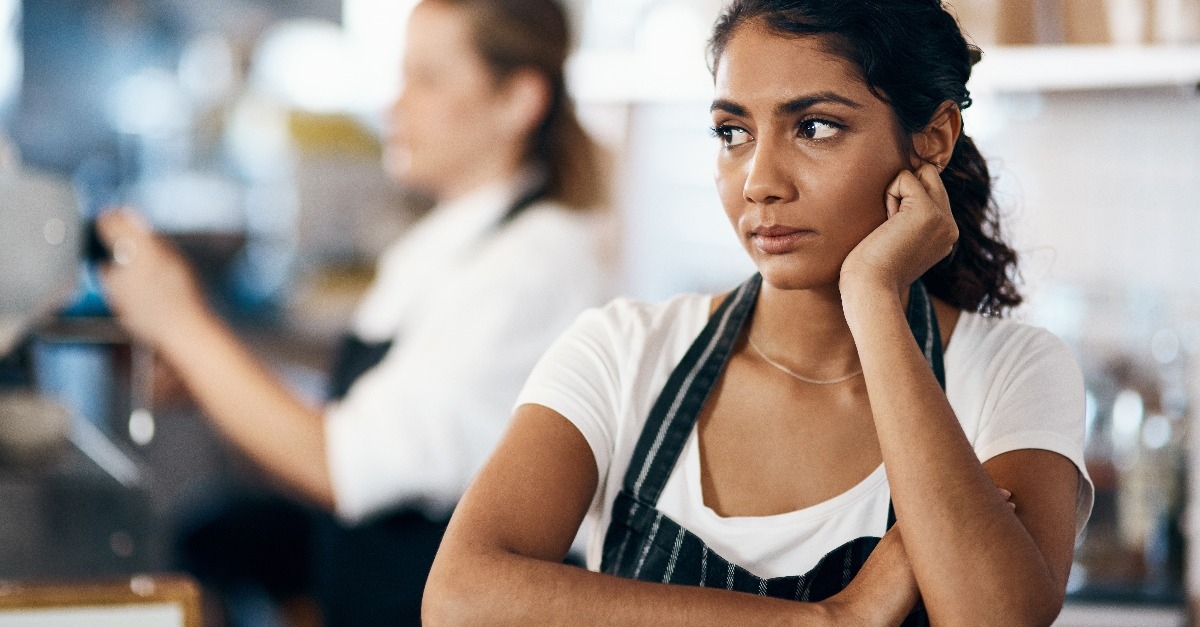 young woman looking unhappy while working behind the counter of a cafe