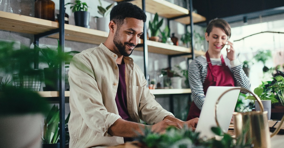 shop assistants with laptop working in potted plant store