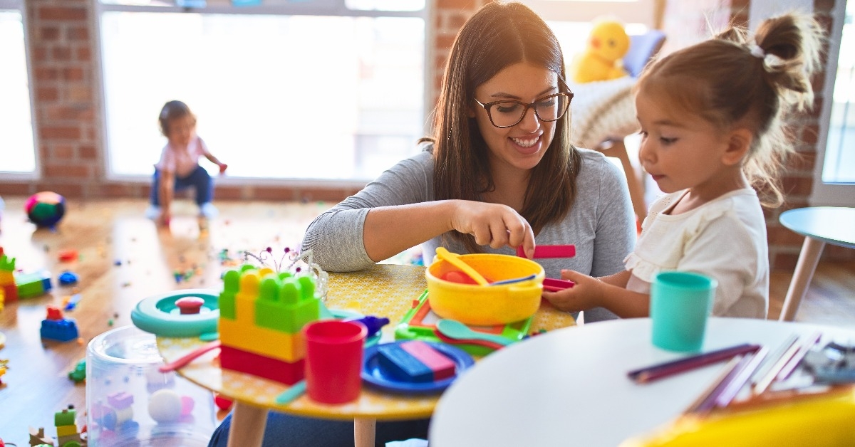 teacher and toddlers playing on the table with lots of toy