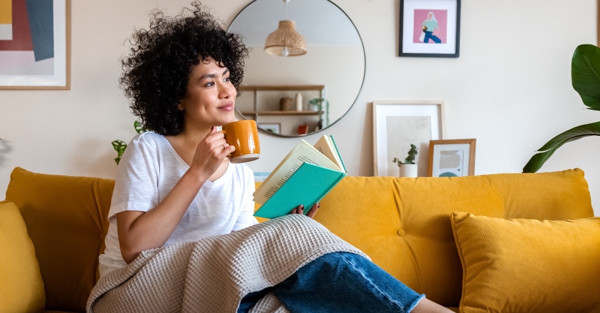woman reading a book at home while drinking coffee