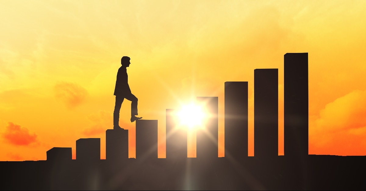 businessman silhouette climbing chart bars at sunset