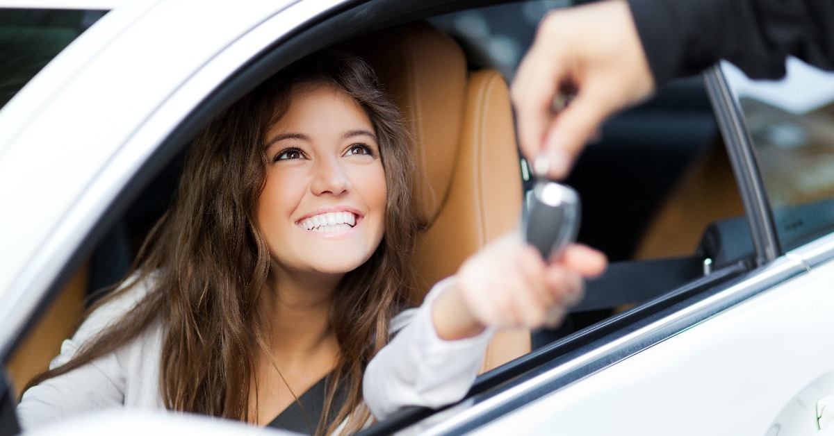 woman receiving keys of her new car from dealer