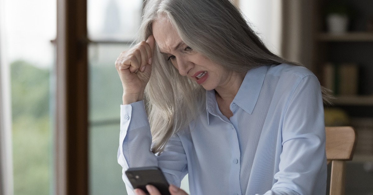 senior businesswoman sitting at desk look at smartphone screen