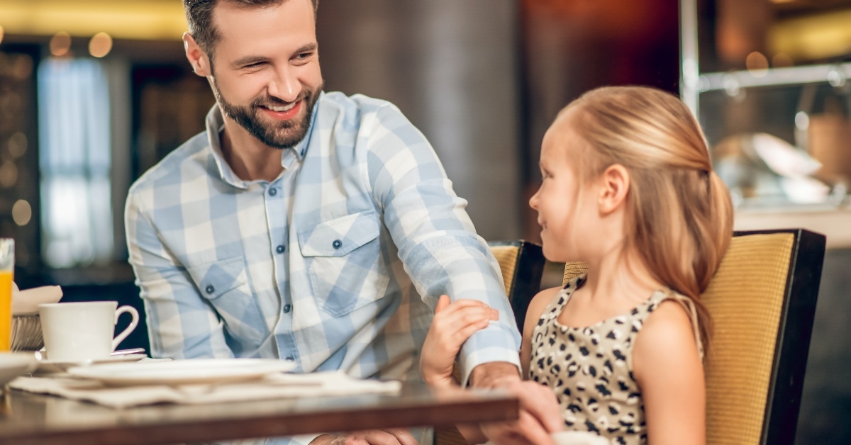 dad putting napkin on top of  daughter's lap