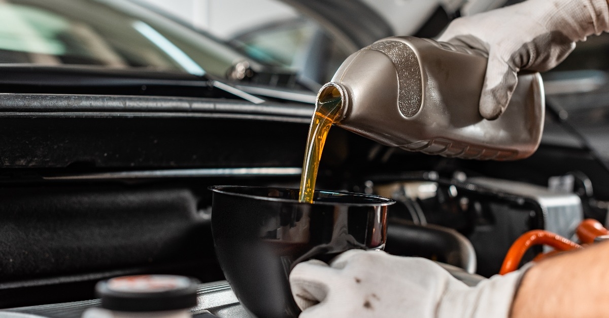 mechanic pouring motor oil at car engine