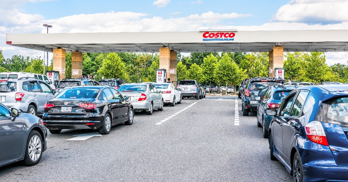 people in cars waiting in long line queue lanes to fill up vehicles with gas 