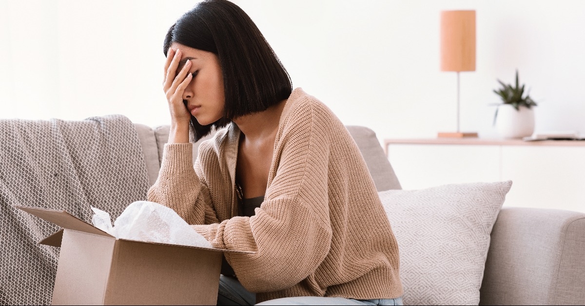 sad young lady unpacking wrong parcel