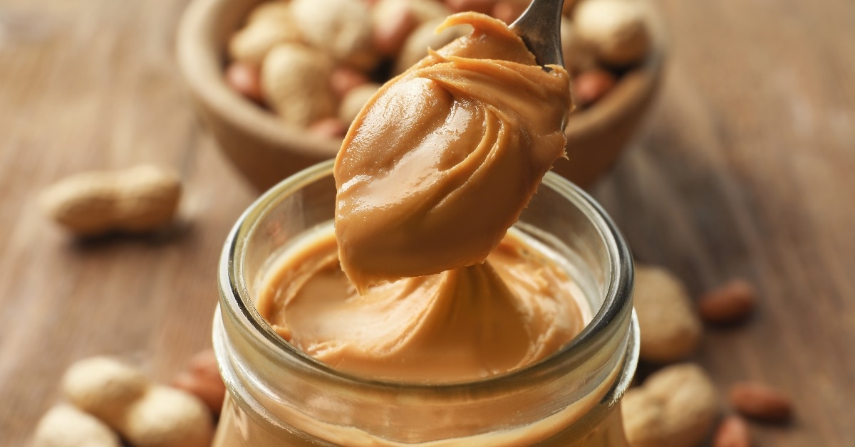 spoon and glass jar with creamy peanut butter