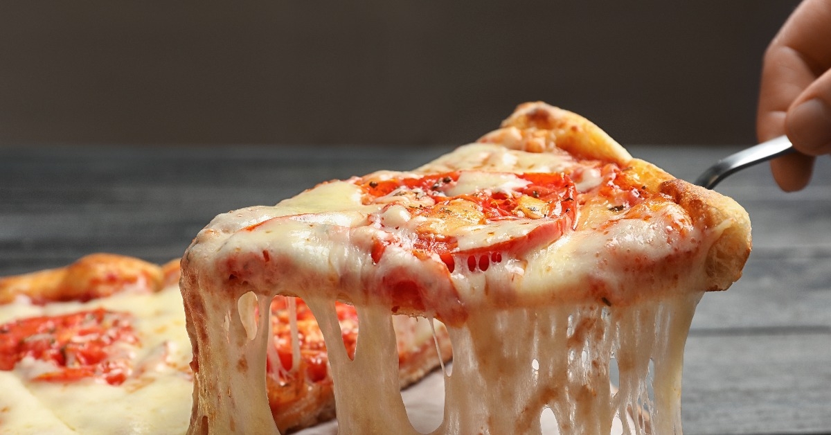 woman taking slice of hot cheese pizza