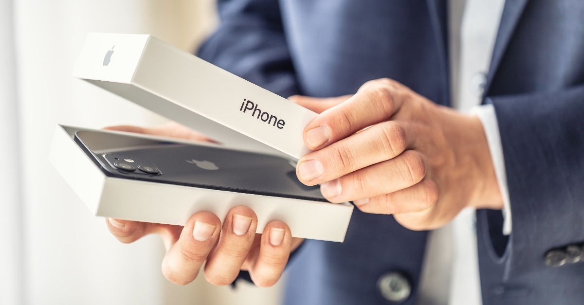 businessman in suit holding in hands and opening a box with iPhone