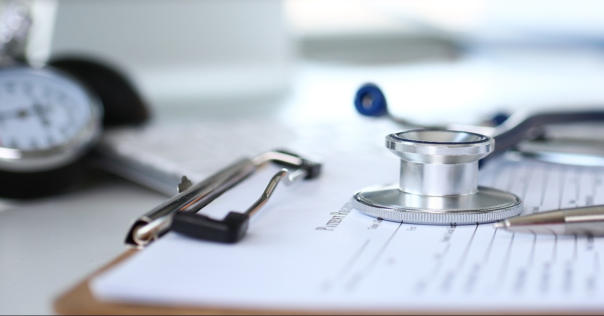 stethoscope head and silver pen lying on medical application form
