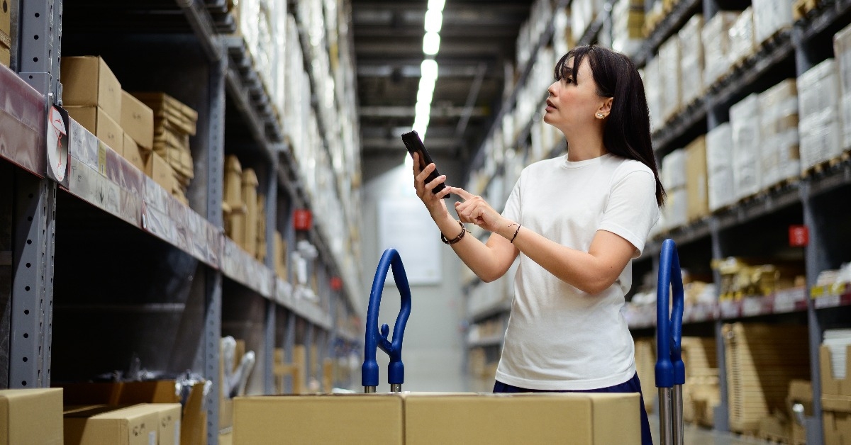 woman using smartphone checking products in a furniture warehouse