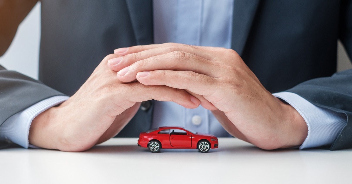 businessman hand cover or protection red car toy on table