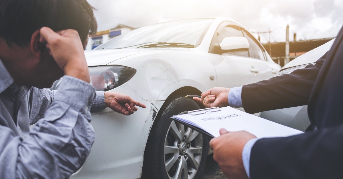 man agent filling insurance form near damaged car