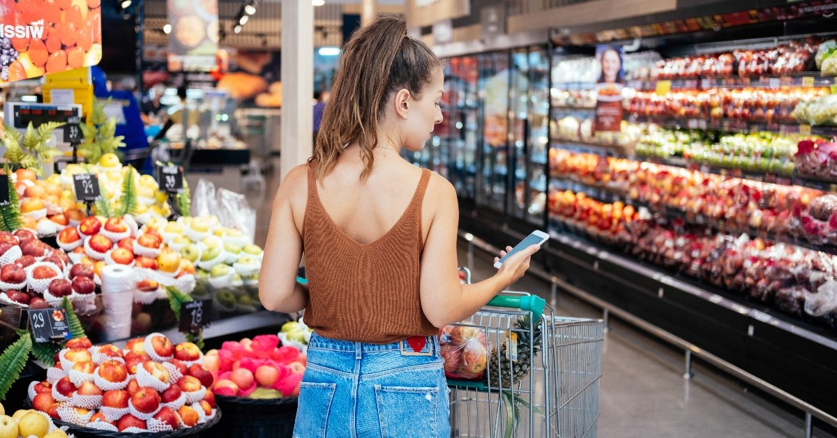 Woman grocery shopping looking at list on her phone