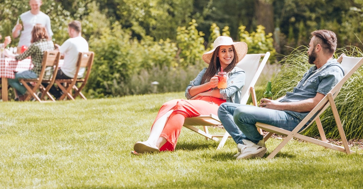 woman and man sitting on deckchairs and flirting during afternoon yard party