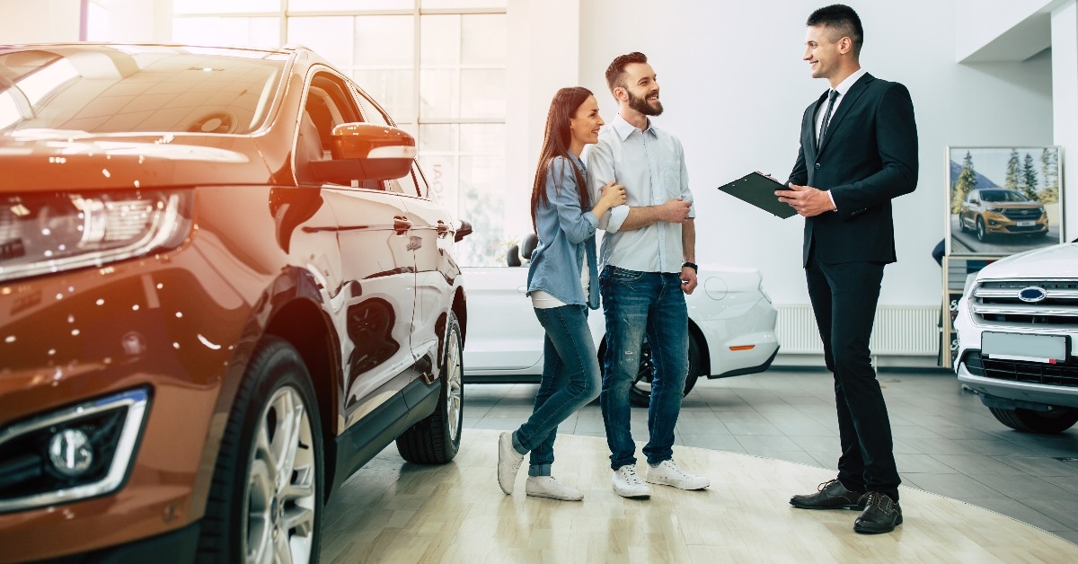 couple buying a new car in city dealership and talking with salesman