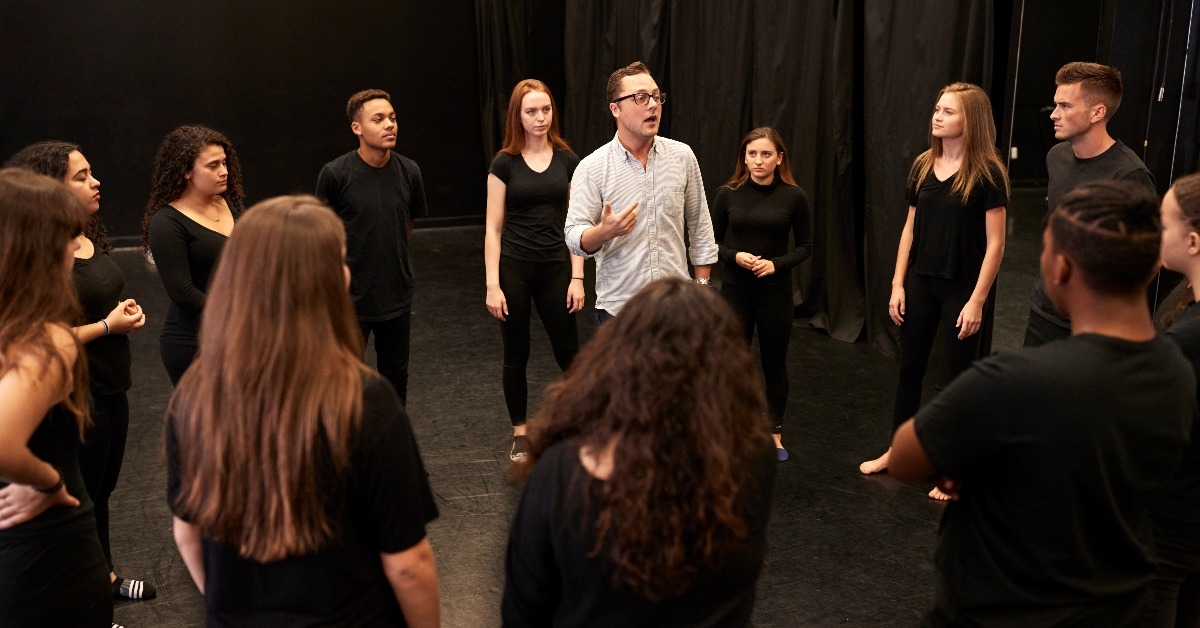teacher with male and female drama students 