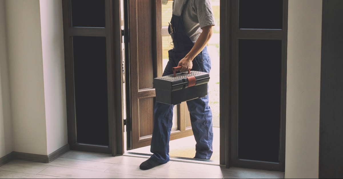 repairman is coming in the house with toolbox in his hand