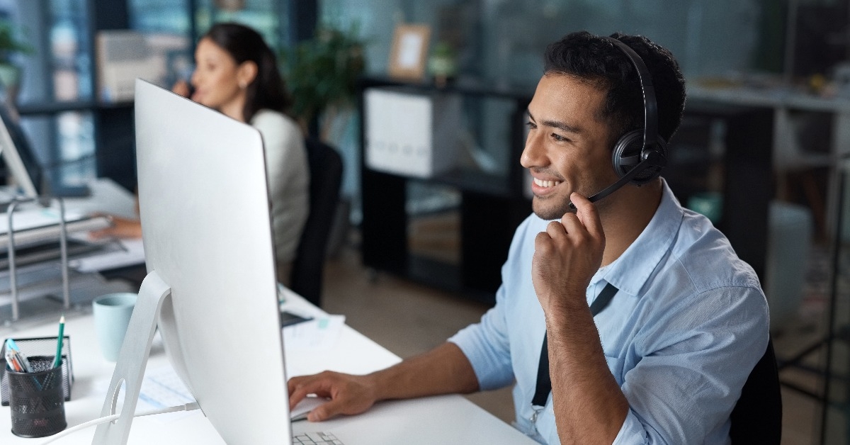  young man using a headset and computer in a modern office