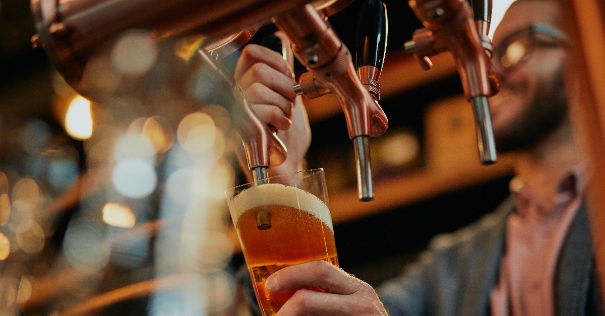 barman pouring beer while standing in pub