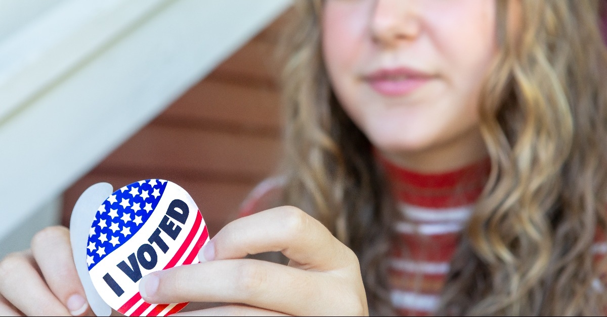 young first time voter female peeling I voted sticker