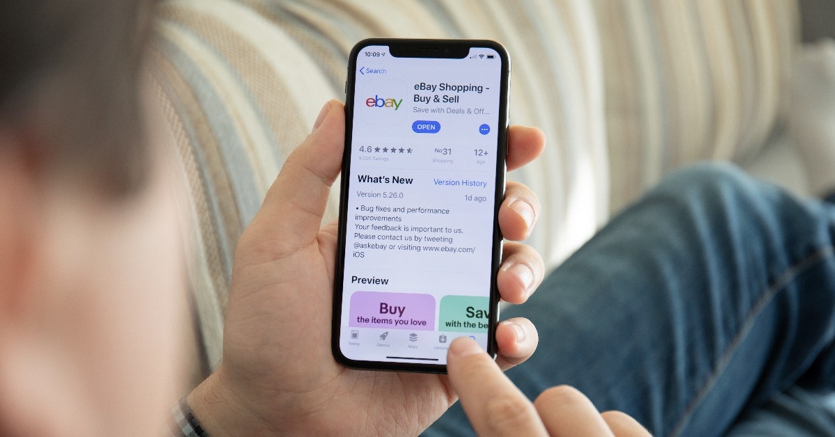 man holding iPhone X with Internet shopping service eBay