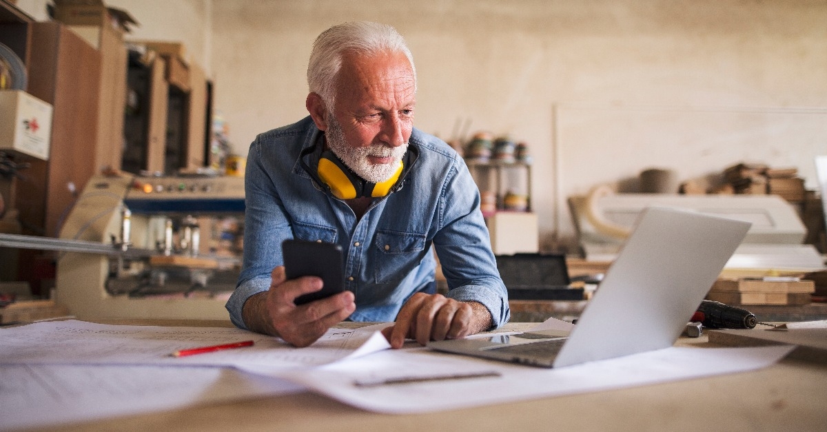 engineer holding cellphone and looking at the laptop