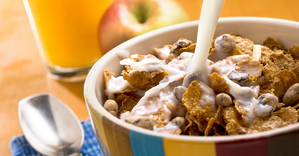 milk pouring over a bowl of cereal with a spoon