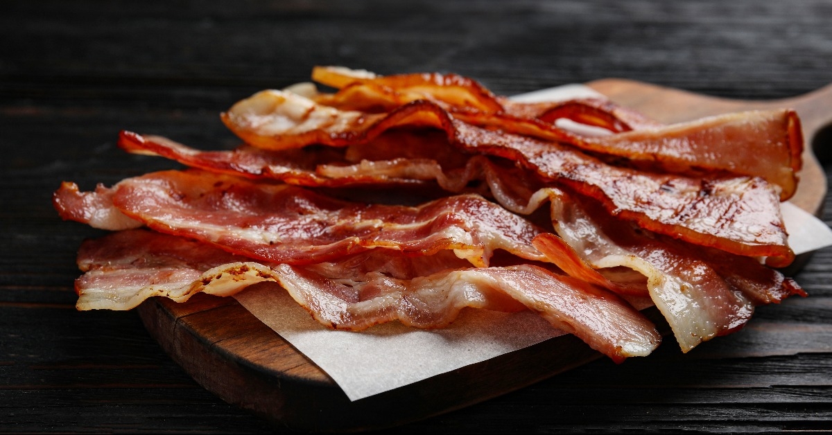 tasty fried bacon on black wooden table